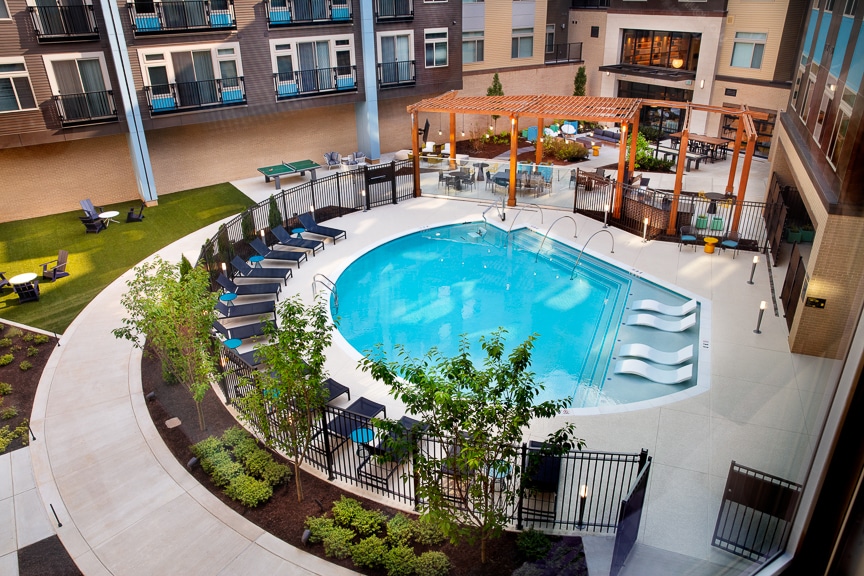 Luxury Apartments in Fairfax for Rent - Scout on the Circle - Aerial View of Sparkling Pool Surrounded By Lounge Chairs and Lush Landscaping