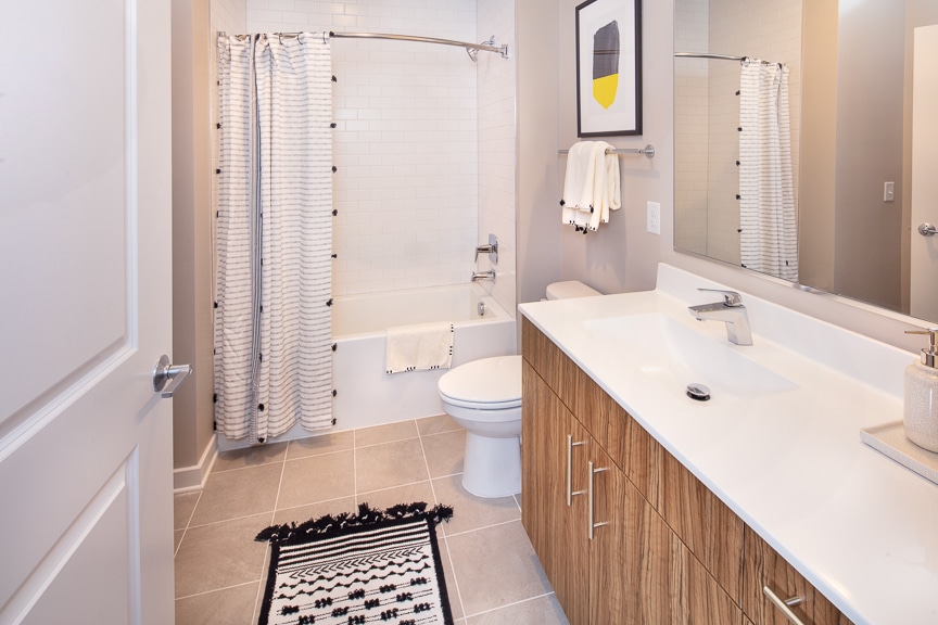bathroom with quartz vanity, decorative artwork, shower and toilet at scout luxury fairfax apartments