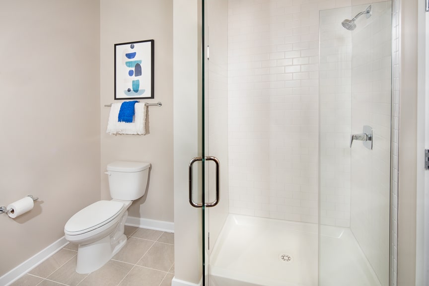 bathroom with glass walk in shower, toilet and decorative artwork at scout luxury fairfax apartments
