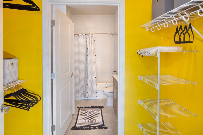 walk in closet with yellow accent walls, shelving and view of bathroom at scout luxury fairfax apartments