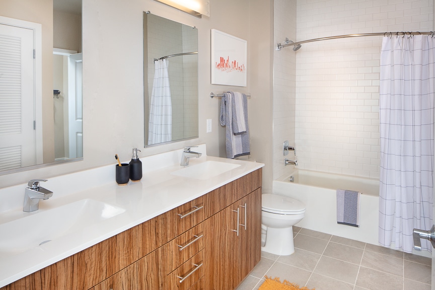 bathroom with tan cabinets, dual vanities tub and toilet - scout luxury fairfax apartments