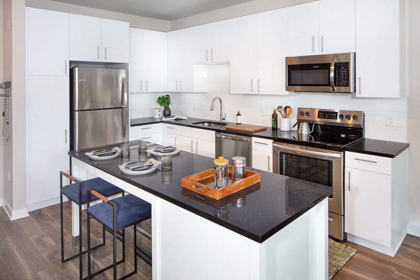 Luxury Fairfax Apartments - Scout on the Circle Chef-Inspired Kitchen with Black Quartz Countertops, White Cabinetry, While Tile Backsplash, Stainless Steel Appliances, and Kitchen Island with Modern Seating