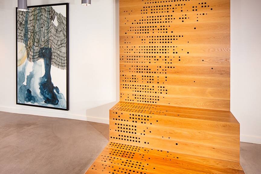 Black, grey, blue, and white abstract art next to a wooden sculpture with holes at scout Fairfax luxury apartments