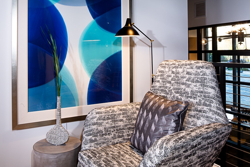 Light and cobalt blue art piece next to grey and white stuffed chair at scout Fairfax luxury apartments