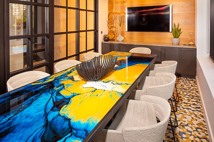 Colorful conference room table large monitor, modern artwork, and storage cabinet at scout fairfax luxury apartments