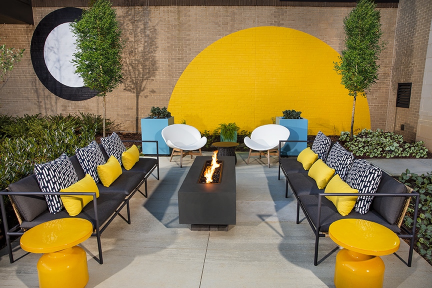 Outdoor seating area with patio sofa, fire pit, and colorful cocktail tables at scout Fairfax luxury apartments