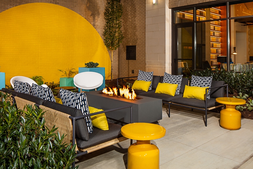 Outdoor seating area with patio sofa, fire pit, and colorful cocktail tables at scout Fairfax luxury apartments