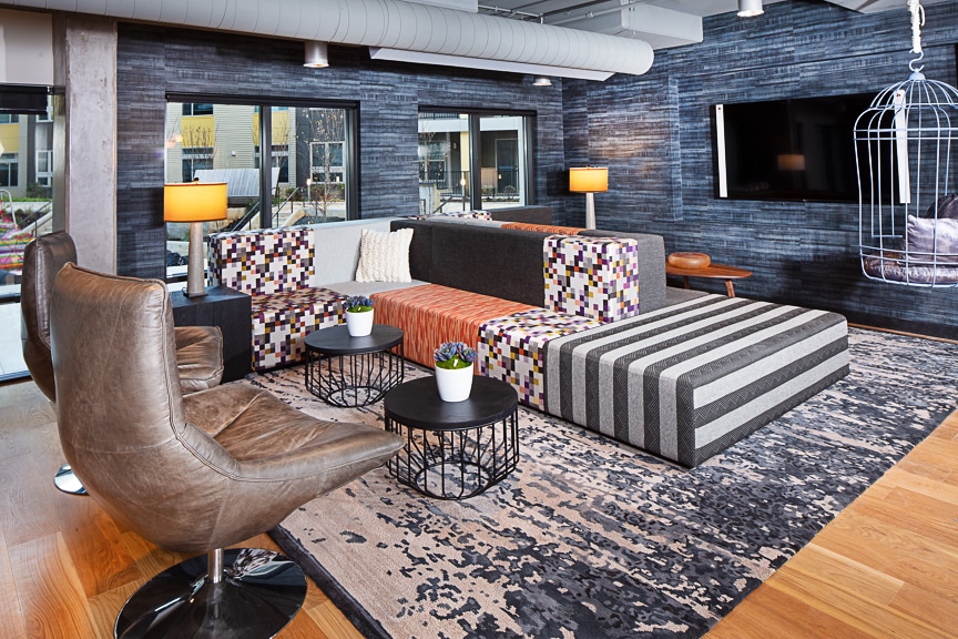 Grey themed lounge with flat screen, leather chairs, social seating, sofas, cocktail tables, and modern lighting at scout Fairfax luxury apartments