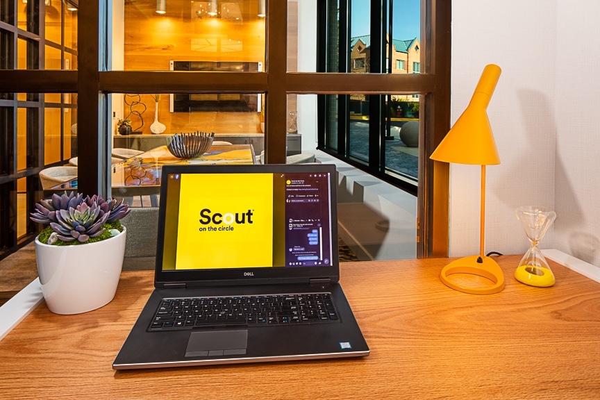 Private working booth with desk, chair, laptop, modern lighting, and view of conference room at scout fairfax luxury apartments