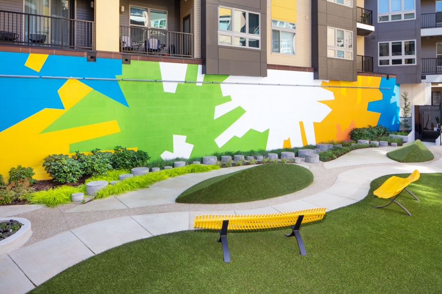 courtyard with social seating, colorful artwork, lush green space, and views of apartment balconies at scout on the circle fairfax luxury apartments